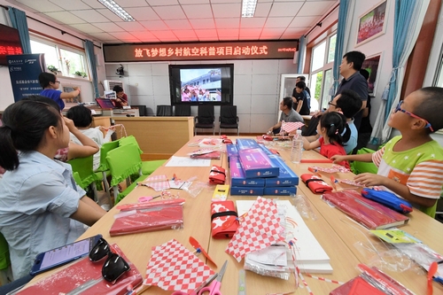 北京和重庆两地跨屏授课的教师带领学生一起学习航空知识、动手制作飞机模型